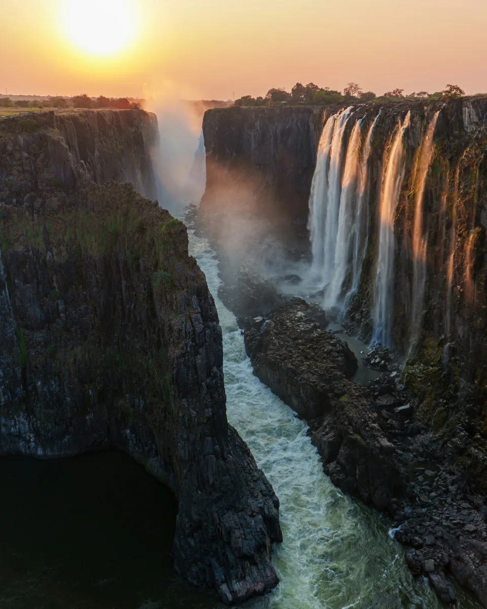 Victoria Falls cascading into a rocky gorge in warm evening light